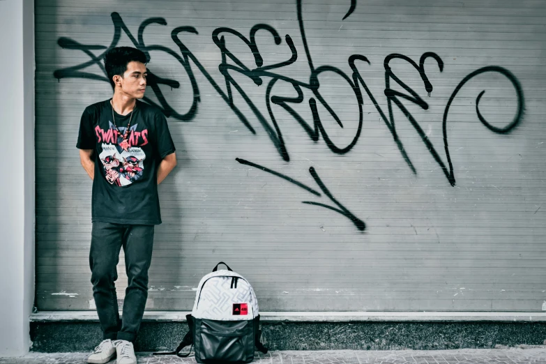 a young man is posing in front of graffiti