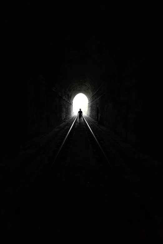 a train track going into a dark tunnel