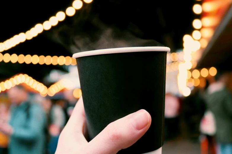 a cup in a hand with a lot of strings on the background