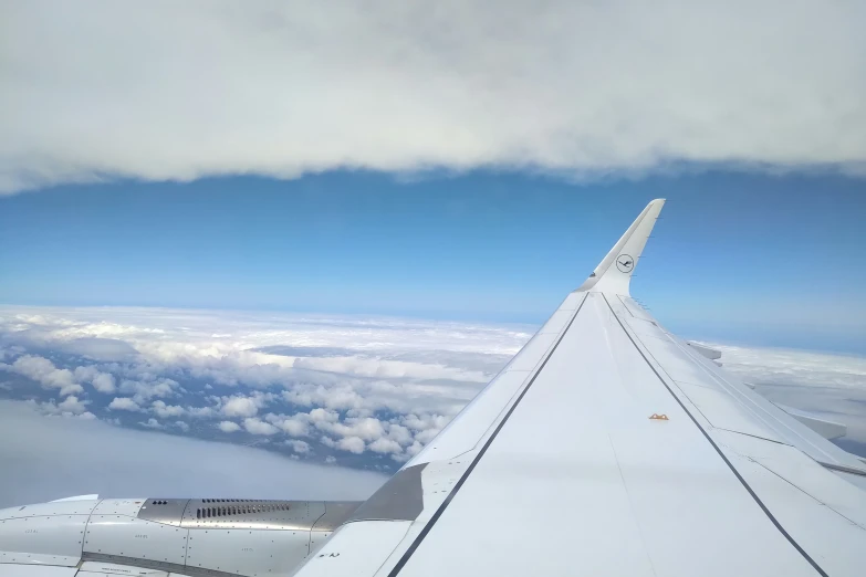 an airplane wing with clouds and a blue sky