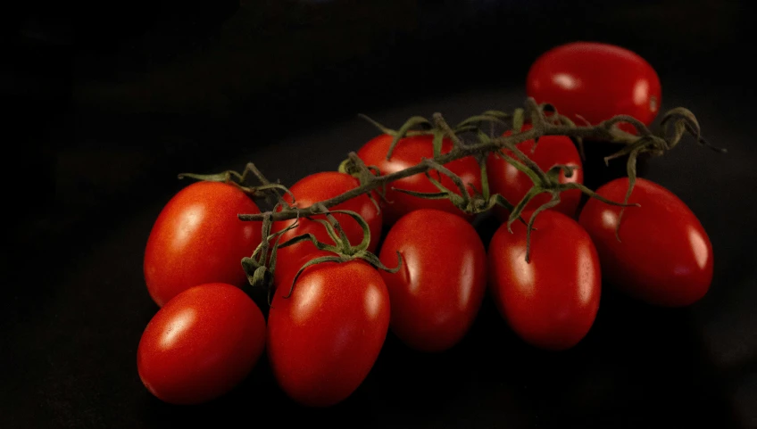 four tomatoes are arranged on top of a black surface