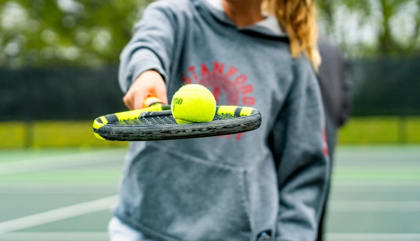 a person holding a tennis racket and three balls