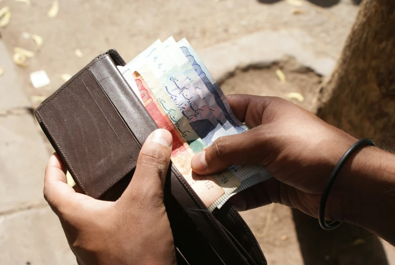 a man taking notes from a leather wallet