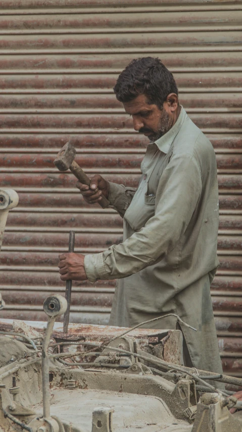 an old man works on soing in front of a garage