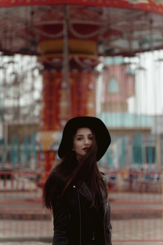 woman in black coat and hat standing at a carousel