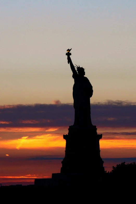 the statue of liberty in silhouette during sunset