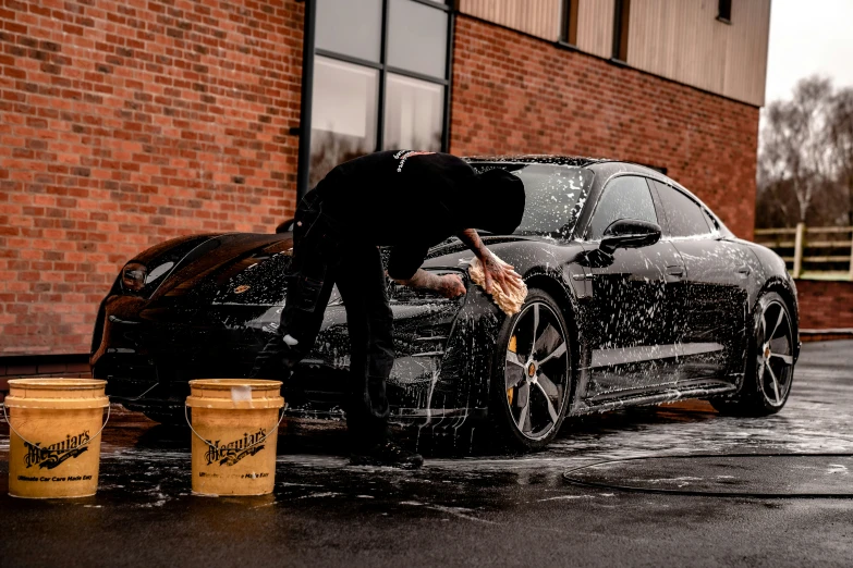 a man washing the car in the street