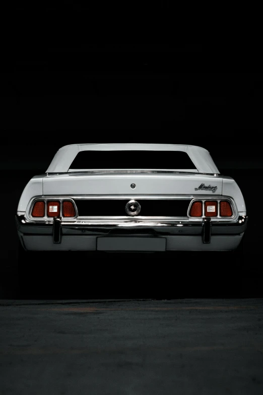 a grey mustang sits parked in a darkened area