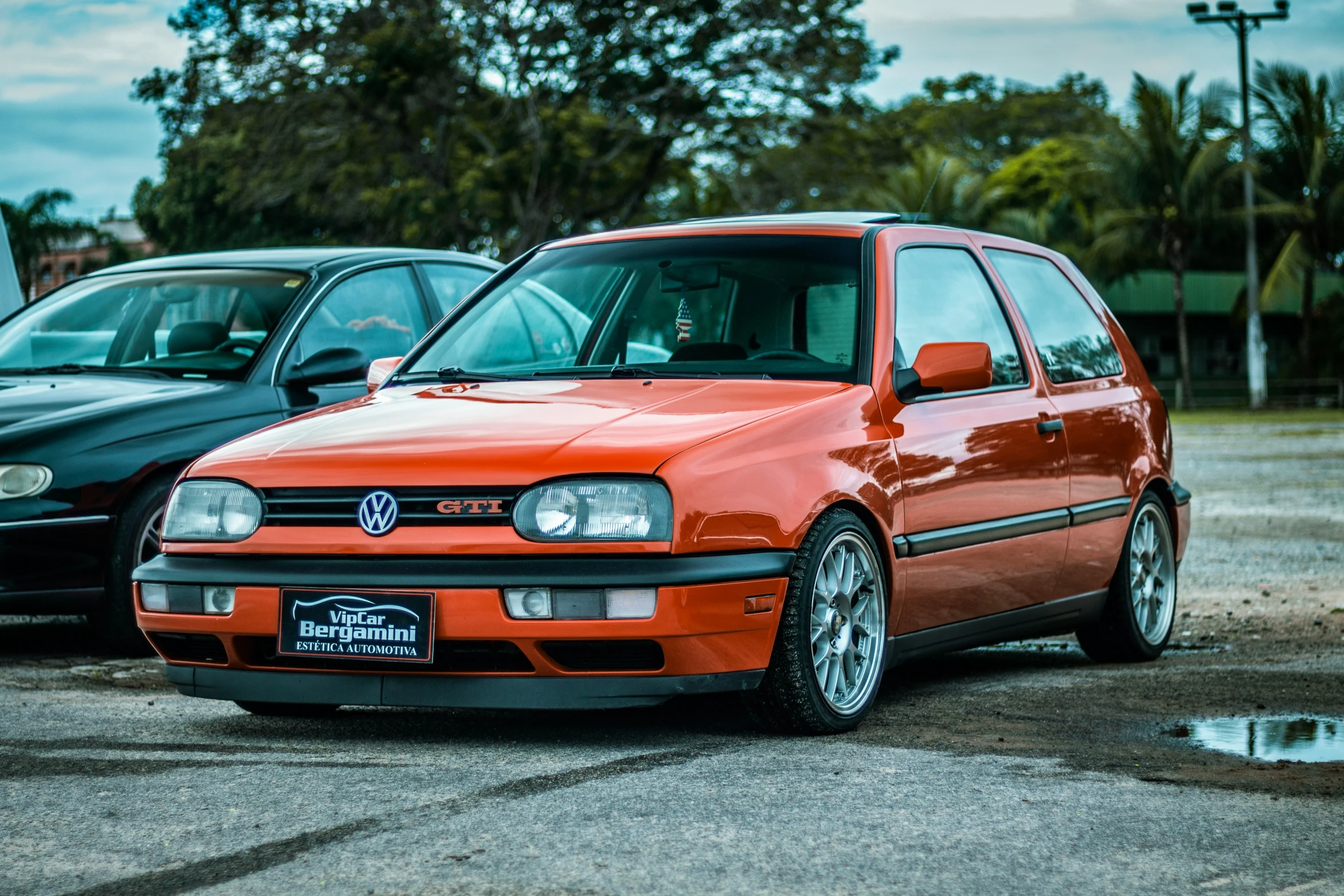 two orange and black cars sitting on top of a parking lot