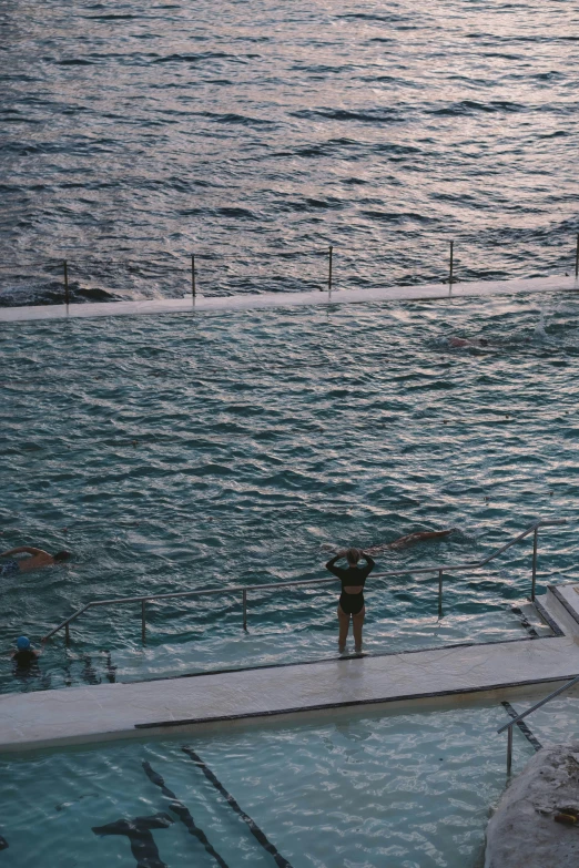 a person standing in the water while standing on the edge of the swimming pool