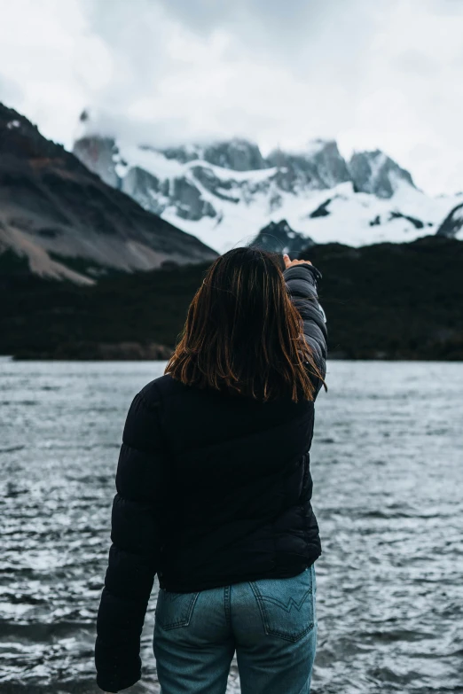 woman standing near a mountain lake and snowy mountains