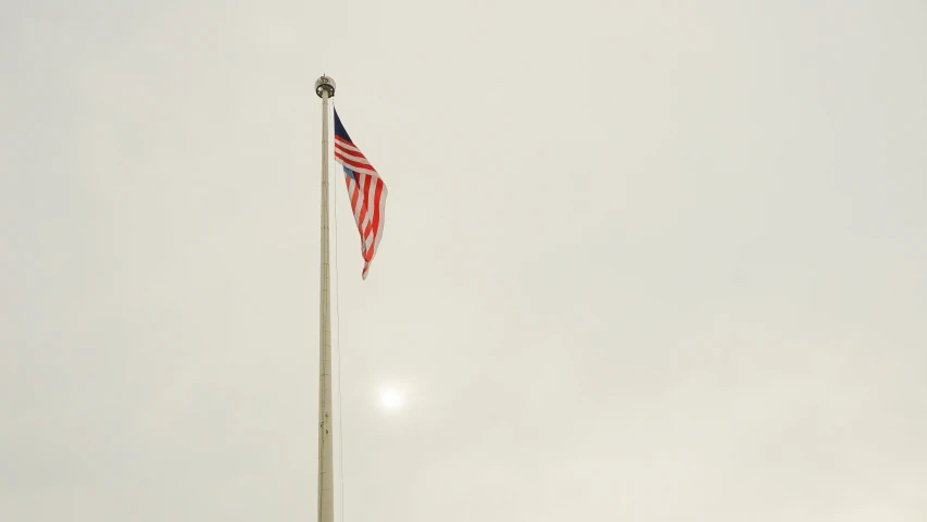 the american flag is at half mast on a very grey day
