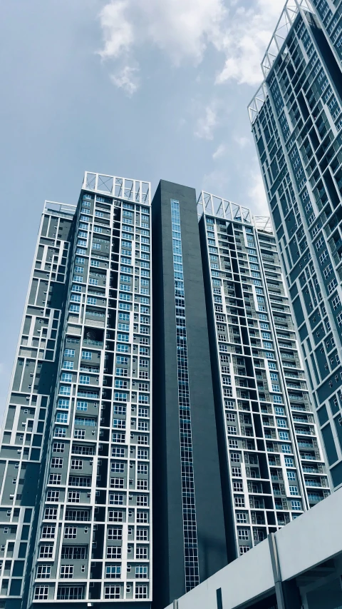 two tall buildings with metal windows against a blue sky