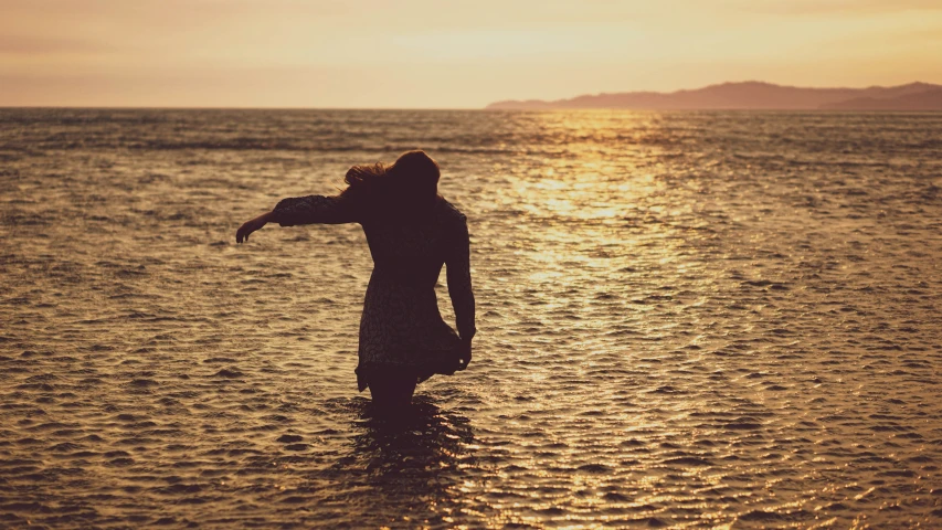 a woman in water with the sun reflecting off her back