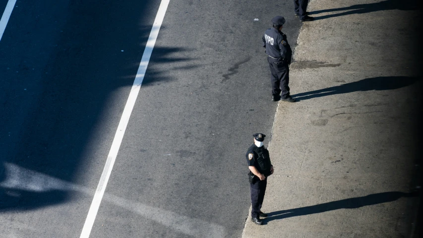 the two cops are standing on the street facing opposite directions