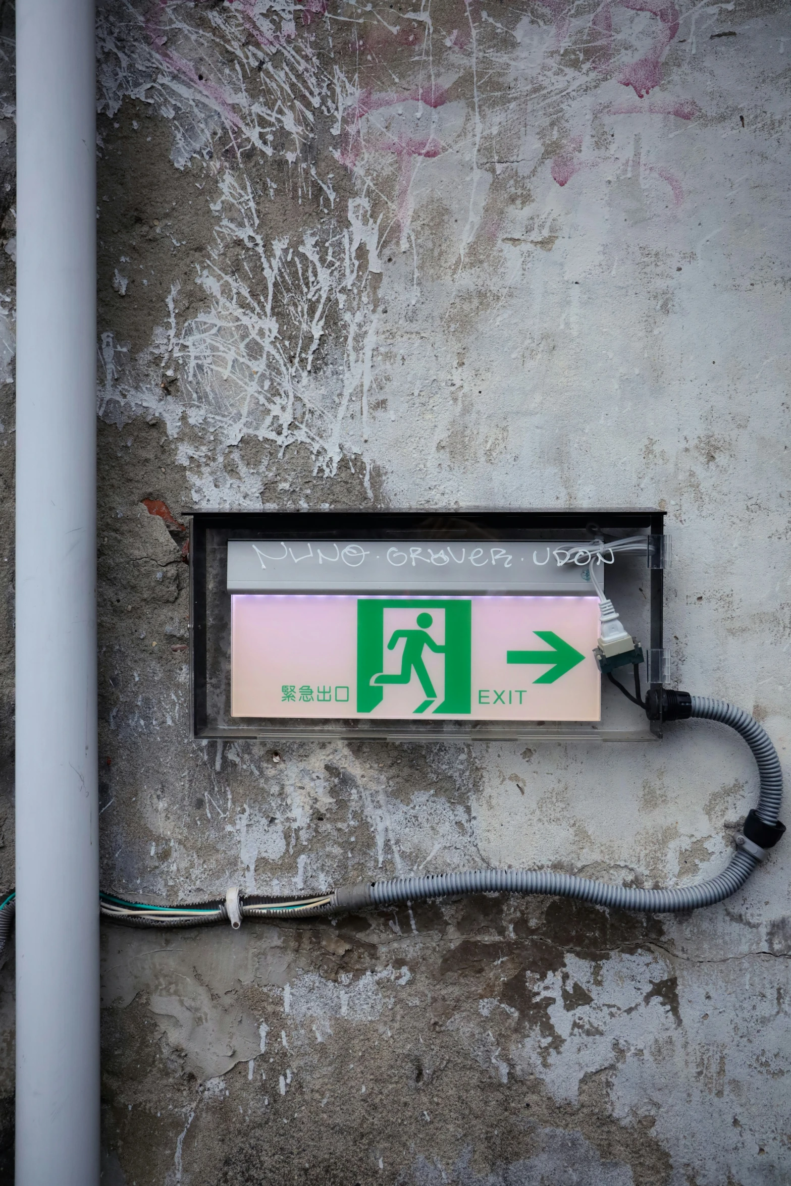 a white and pink fire exit sign mounted to the side of a cement wall