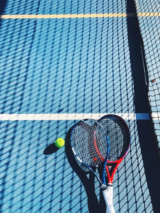 tennis rackets and ball sitting on top of an indoor court