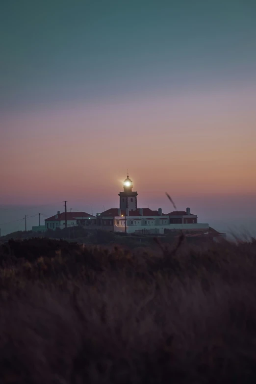 the moon is setting on top of the lighthouse