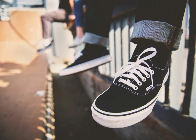 two skate boarders, one wearing striped socks and the other with striped pants and black shoes