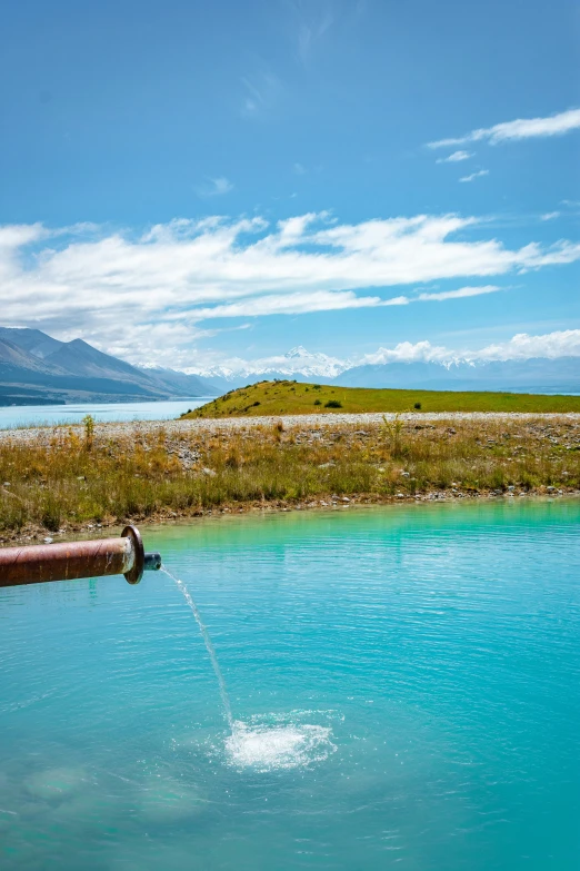 a man is standing on a lake next to a pipe