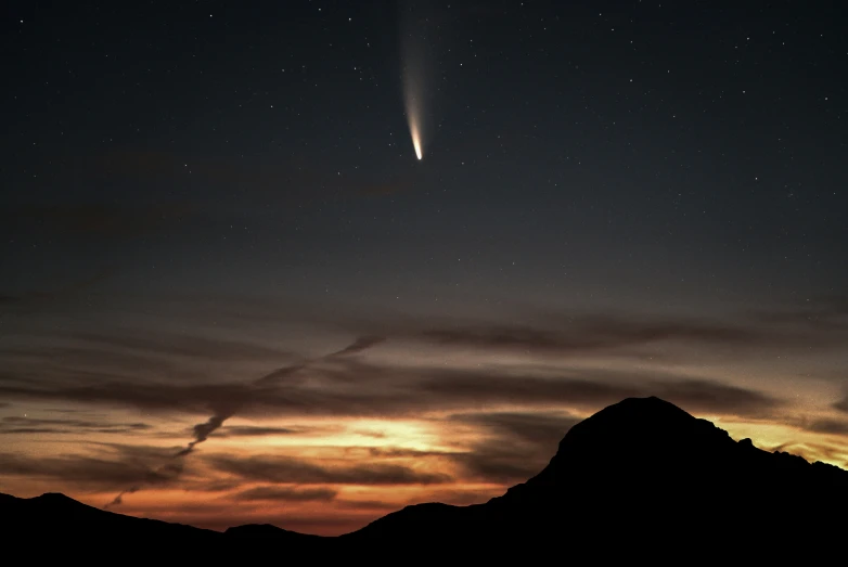 the sky with a rocket in it is shining orange and blue