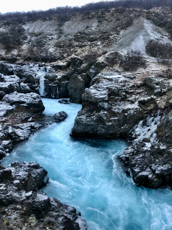 the ice filled water and river runs between rocky terrain