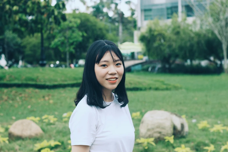 a young woman standing in the middle of a park