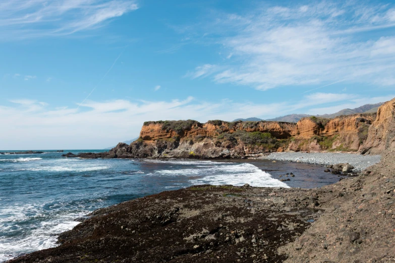 the person is standing on the rocks near the water