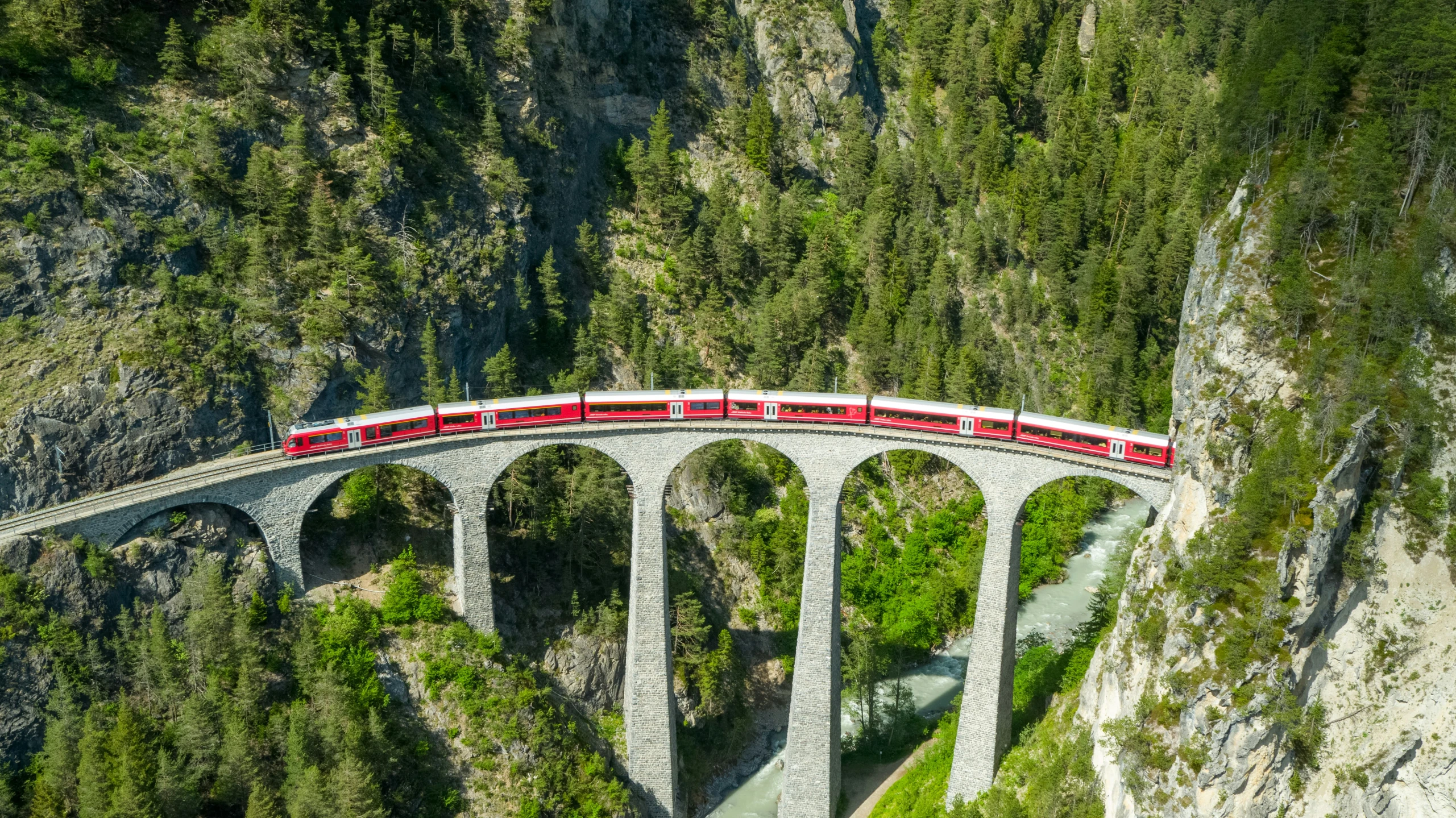 a red train is driving over a bridge