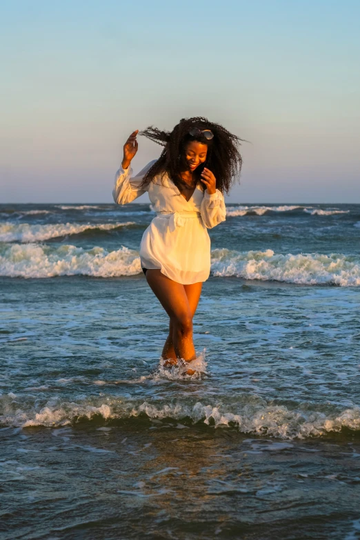 woman in white bathingsuit in ocean and holding umbrella