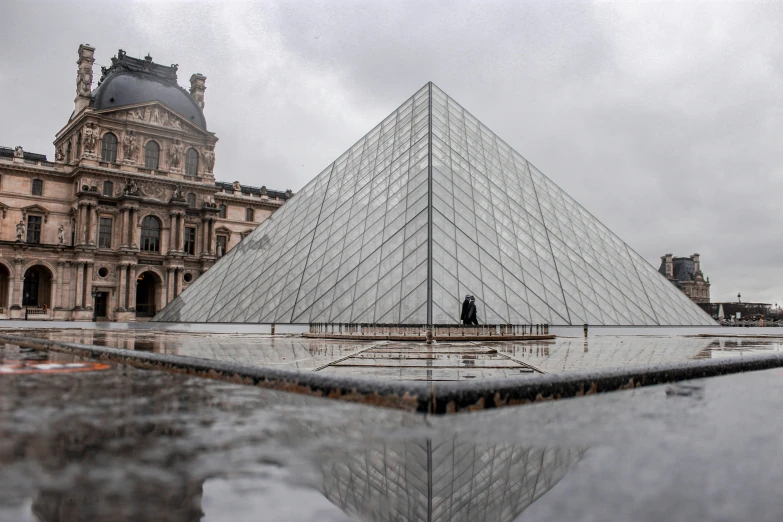 a mirrored pyramid with a man standing next to it