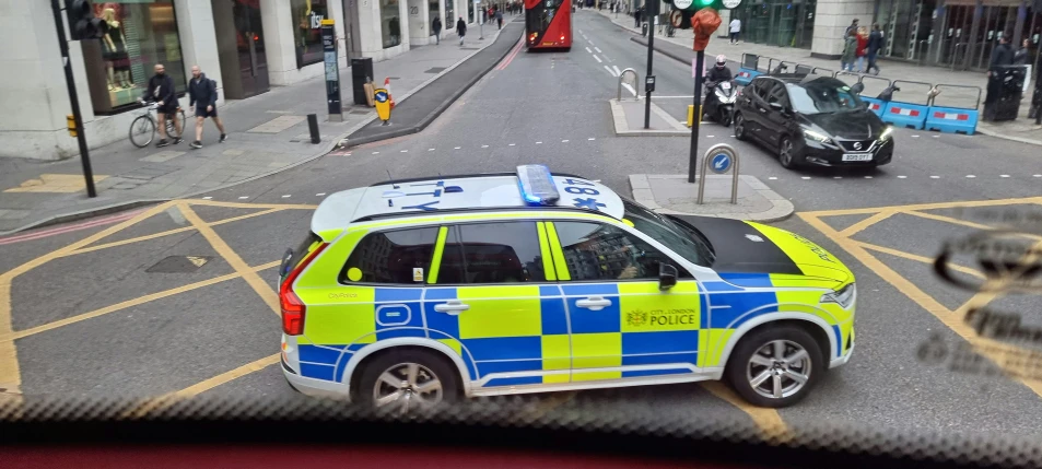 a blue and yellow police car stopped at a stop sign