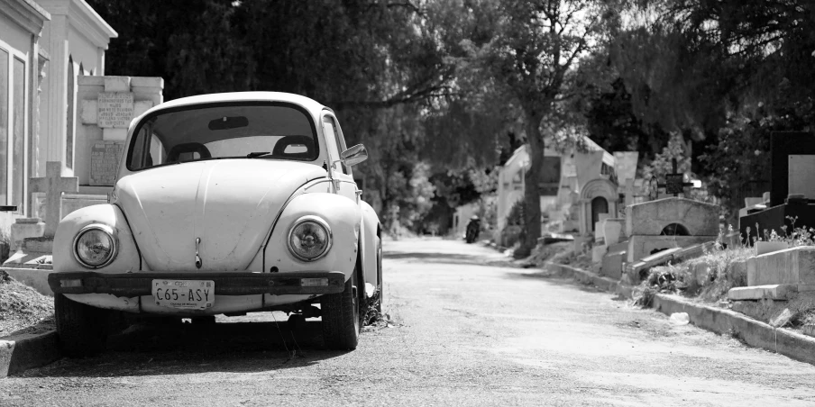 black and white pograph of old car parked in cemetery