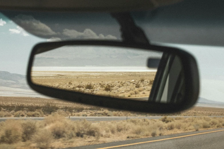 the rear view mirror on the car shows the desert