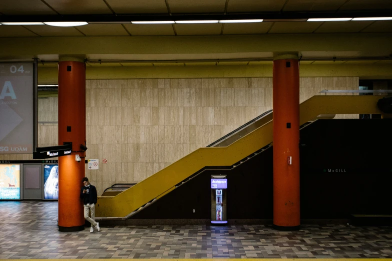 a man in a waiting area beneath the escalator