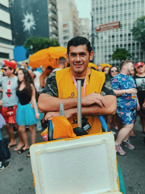 a man in yellow vest carrying a cooler full of umbrellas