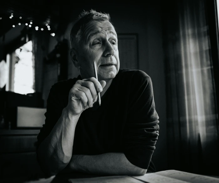 a man is leaning back in front of a table with books on it