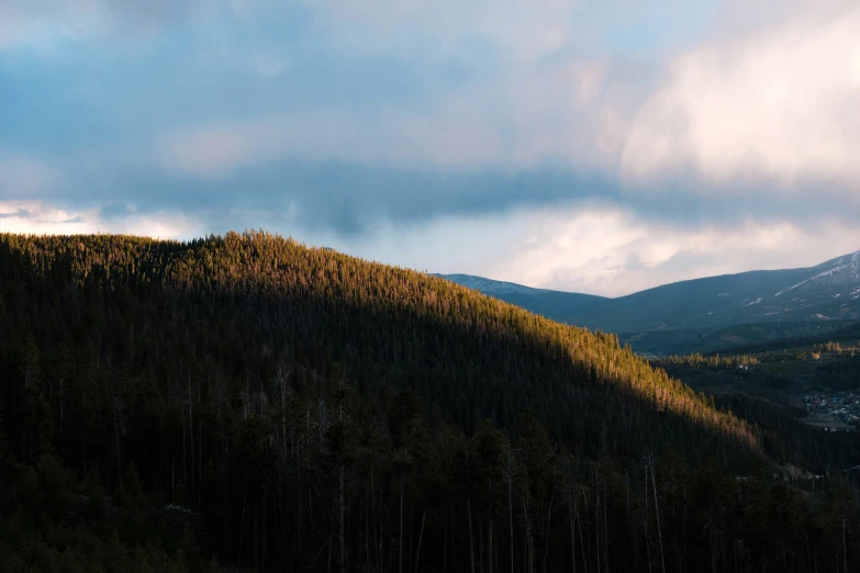 clouds loom over a forest of trees and mountains