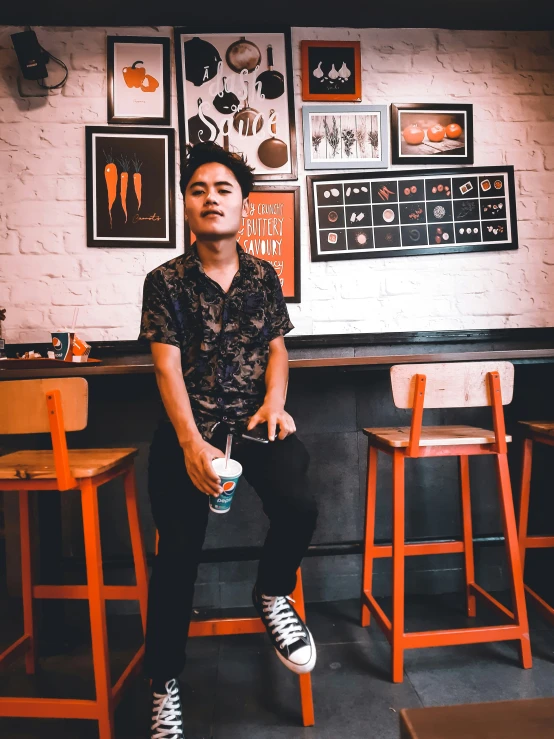 a man in a black and white shirt sitting in a bar with stools