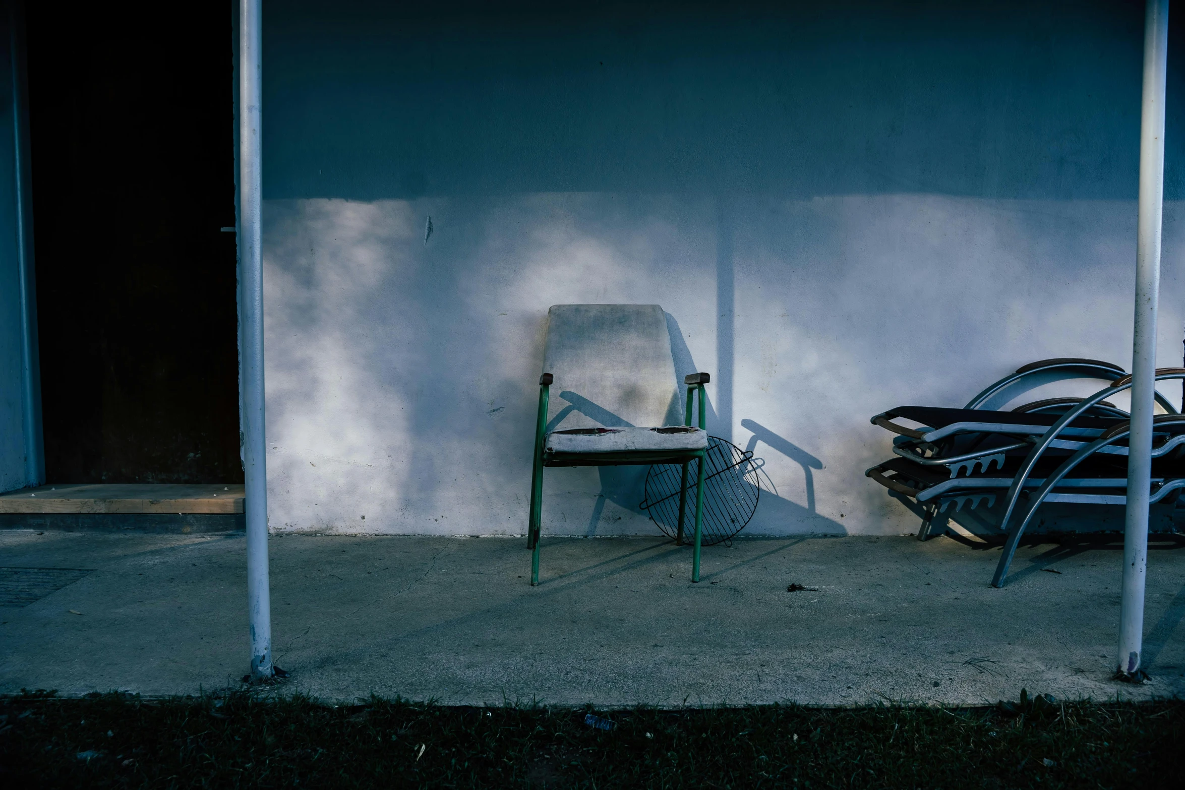 an empty chair on a sidewalk next to a wall