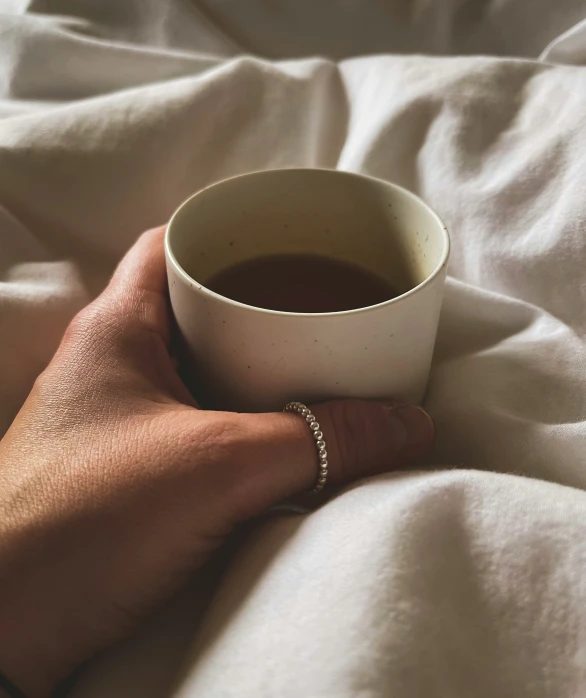 a hand holding a cup of black coffee