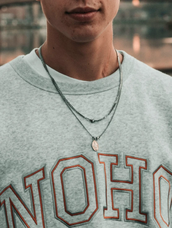 a person wearing a necklace with the name detroit written on it