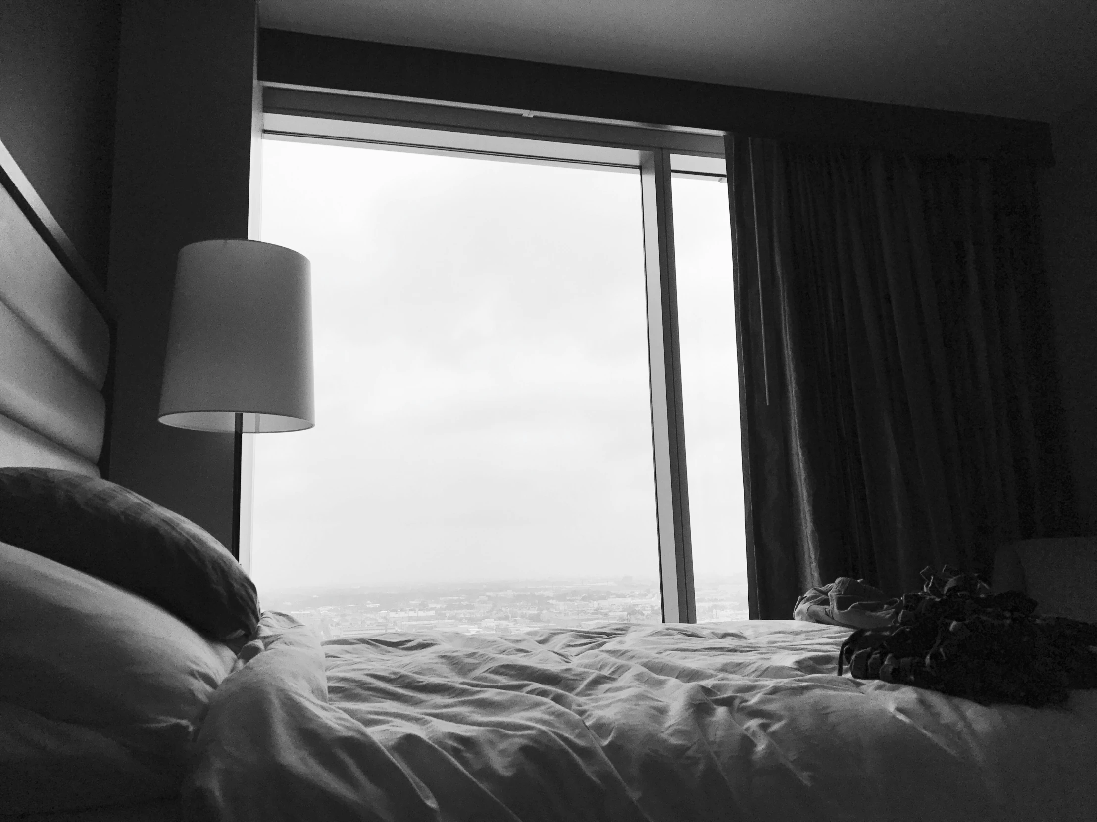 a bedroom with two curtains and a window overlooking the ocean