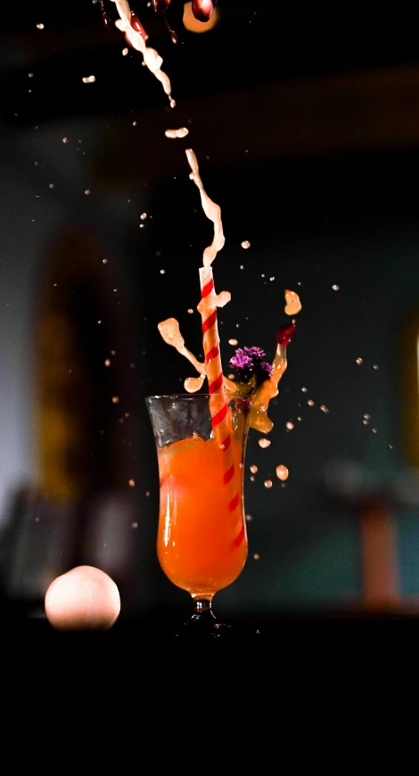 an orange drink being thrown into a glass