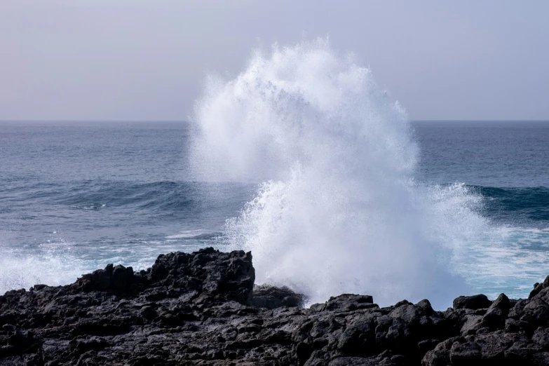 a crashing wave on the beach near the rocks