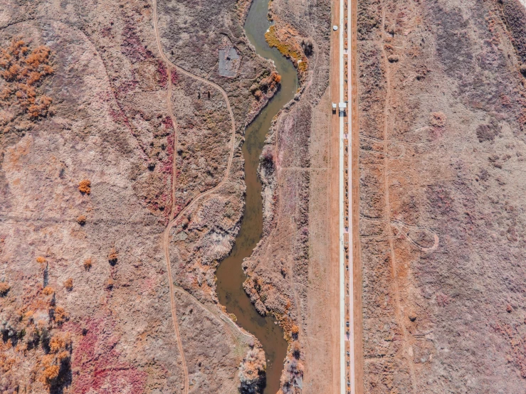 an aerial view of the desert with several trucks driving on it