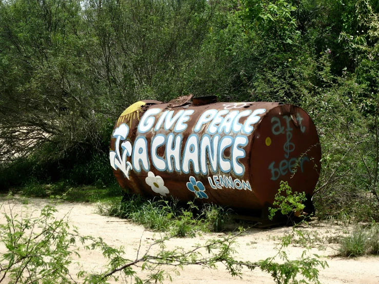 an old oil barrel with graffiti that reads give free war exchange