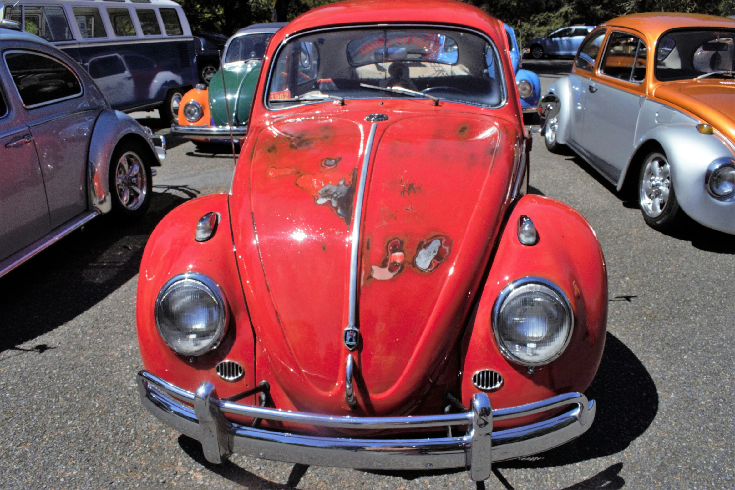 a red, vintage vw beetle sitting in a parking lot