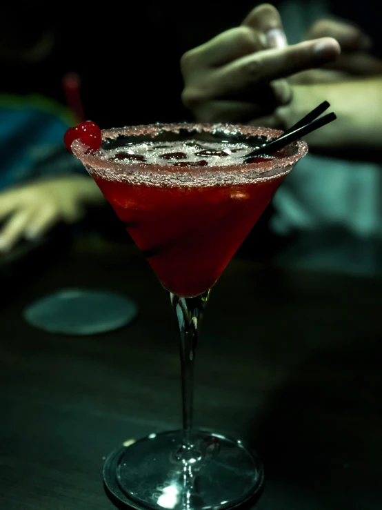 a red cocktail sitting on top of a wooden table