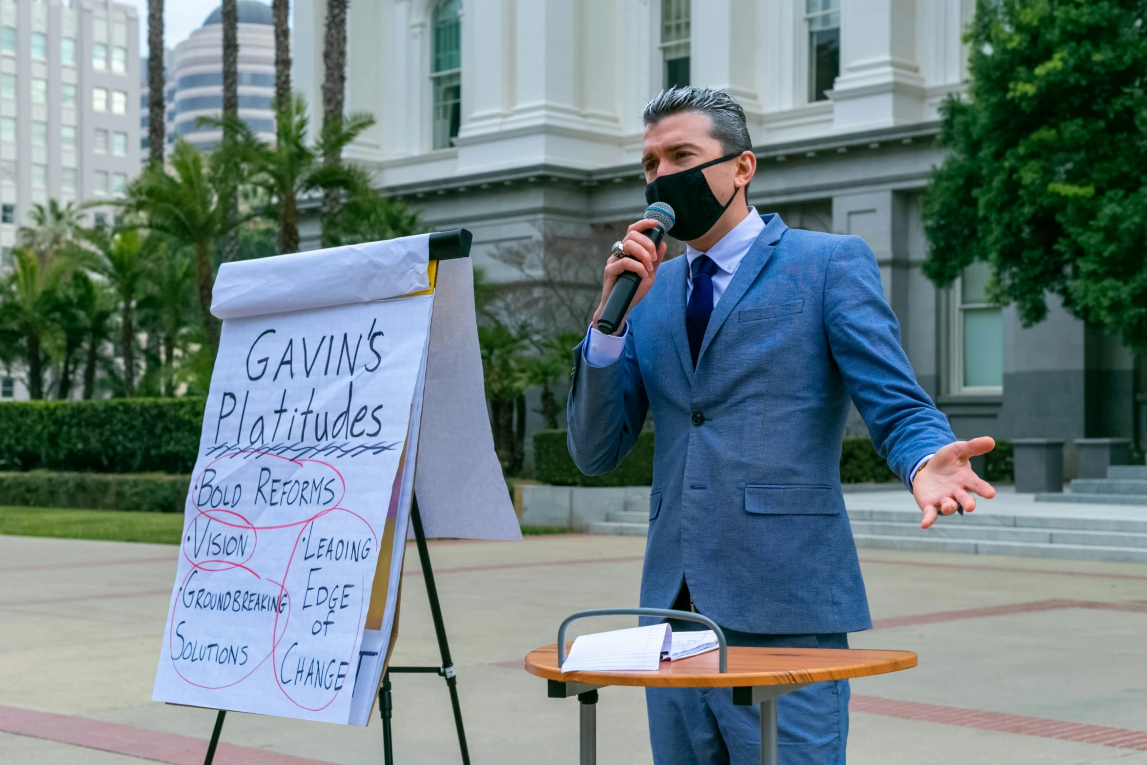 a man wearing a mask stands at a podium and speaks